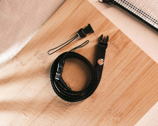 Black quick release kameraseil camera strap for analog and DSLR cameras on wooden surface